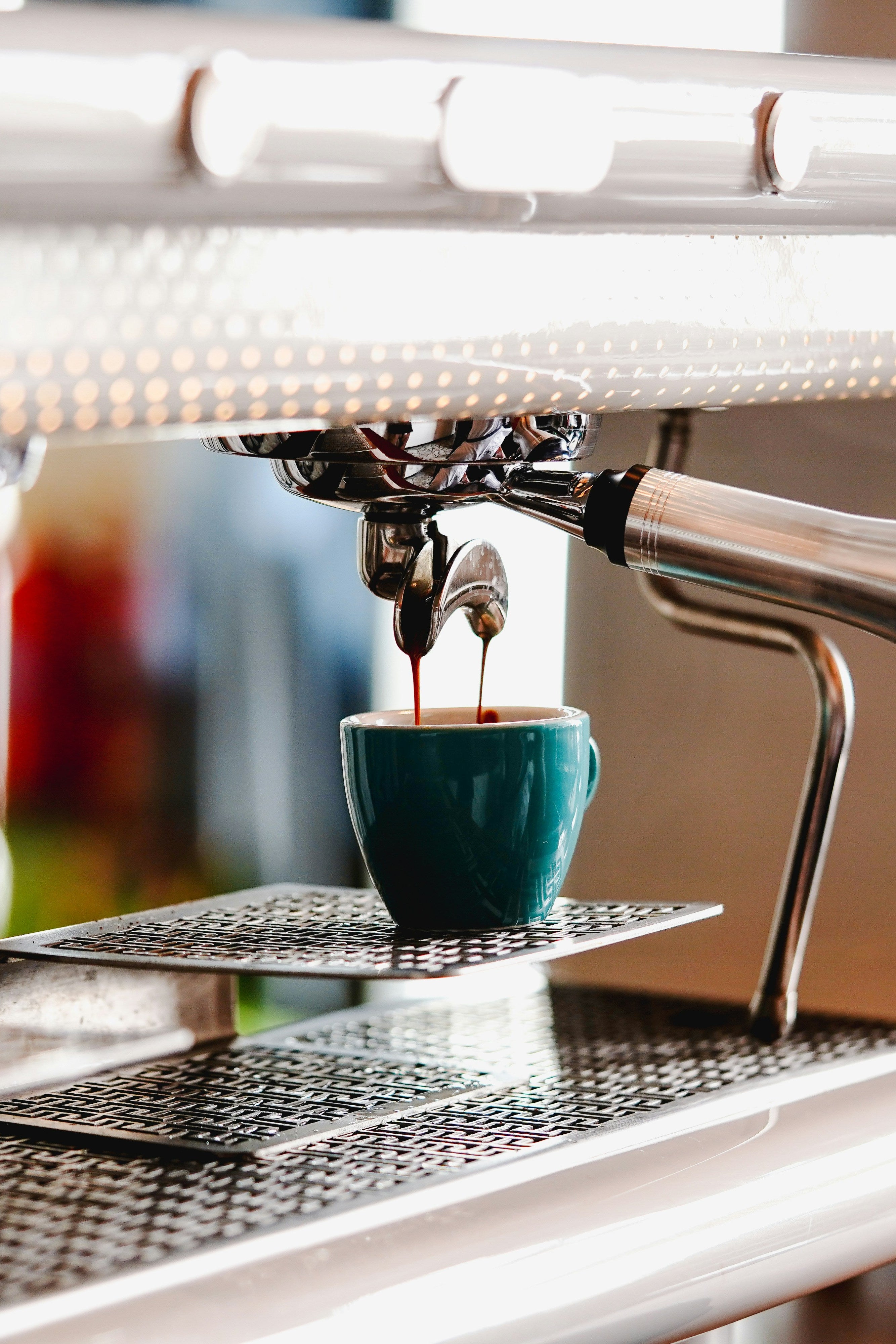 Espresso machine dispensing coffee into a blue cup with a blurred background